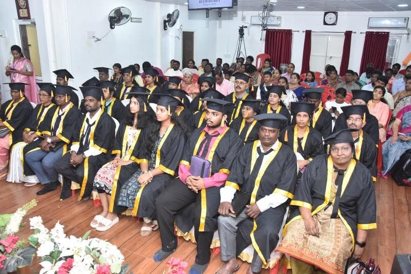 Graduands in gowns seated at a Bible Institute graduation ceremony.