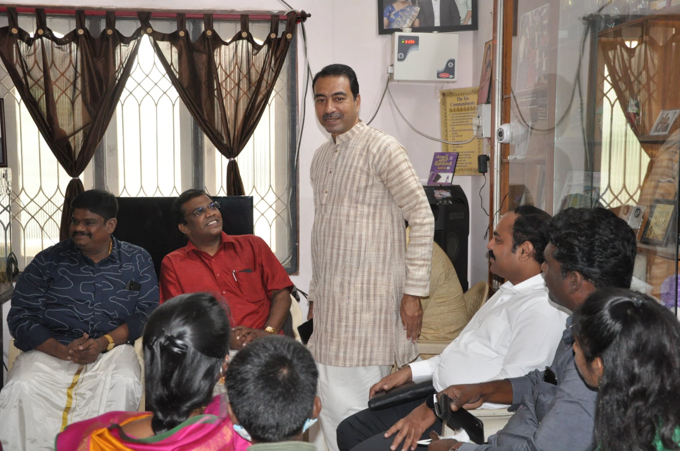 A man speaking to a small group gathered in a home.