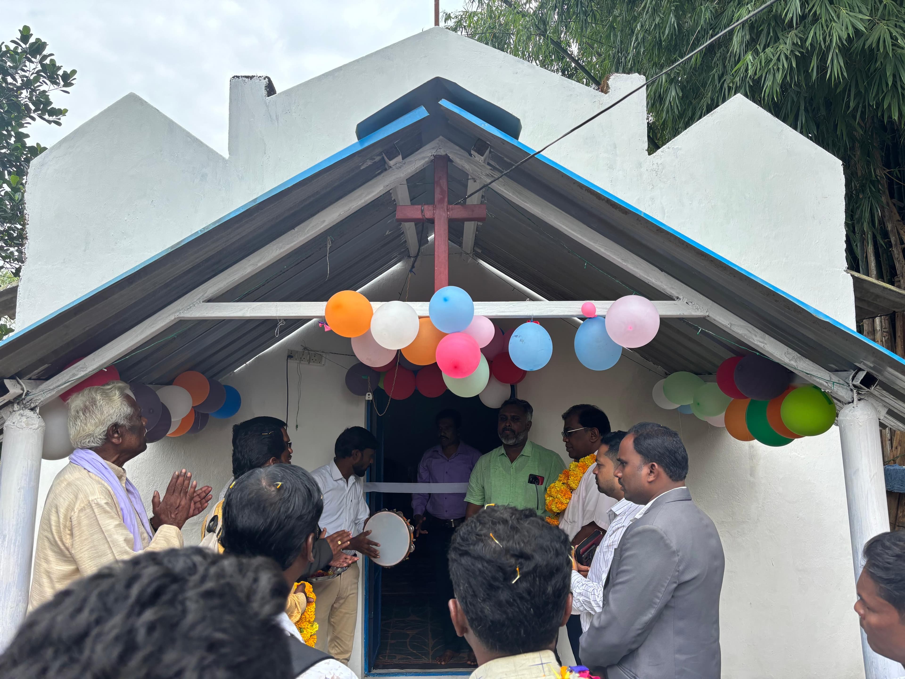 People gathered at the entrance of a newly opened village church.