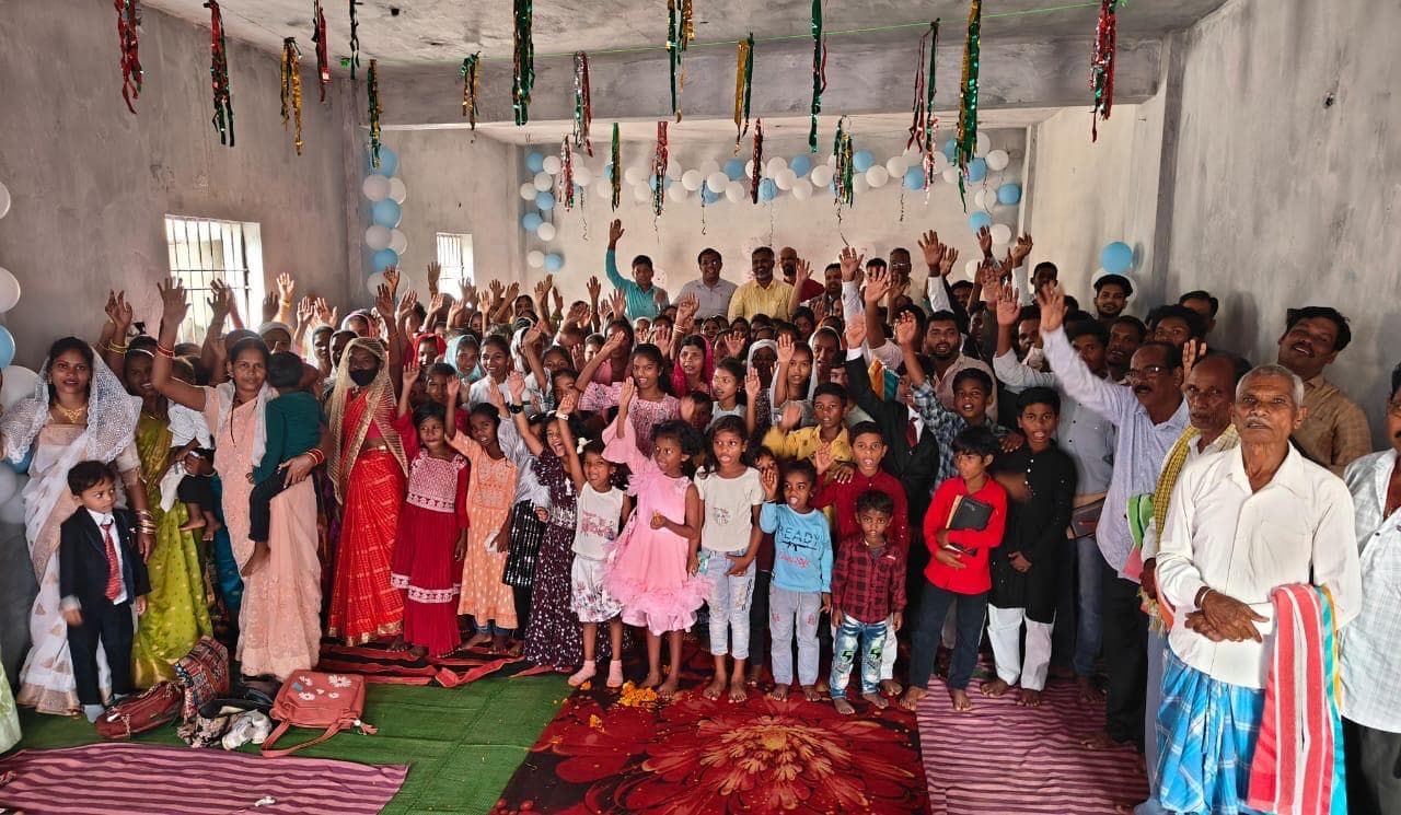 A village congregation with hands raised inside their church.