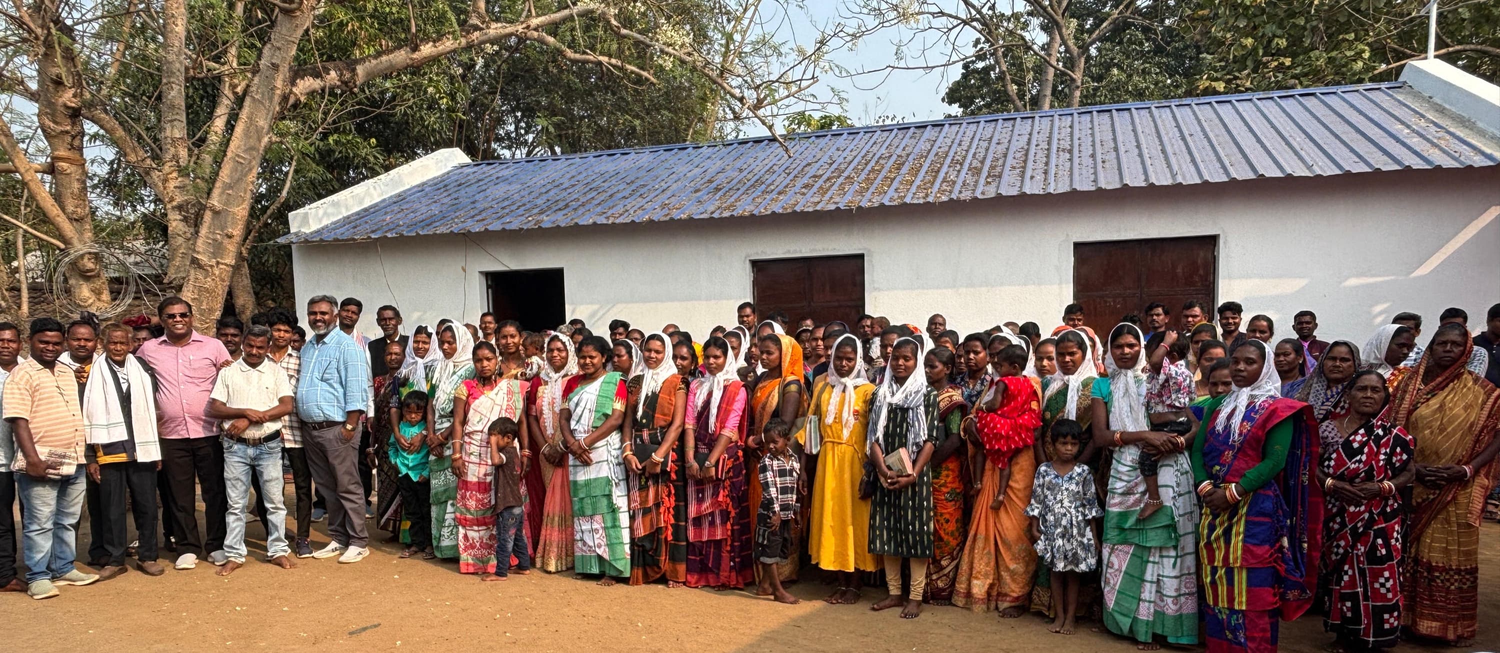A congregation standing outside a village church building.
